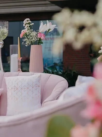 A detail of the lounge seating at Yasha and Rahil's blush wedding, with a focus on the soft pink sofa and elegant floral arrangements.