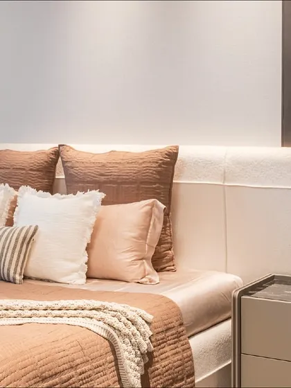 A close-up of the bedding and custom headboard in a Gurugram bedroom. The layers of different textures and earthy tones create a warm and inviting atmosphere.