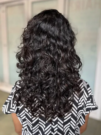 A beautiful example of a curly haircut done by one of our students on a real model, enhancing the natural curl pattern and adding shape.