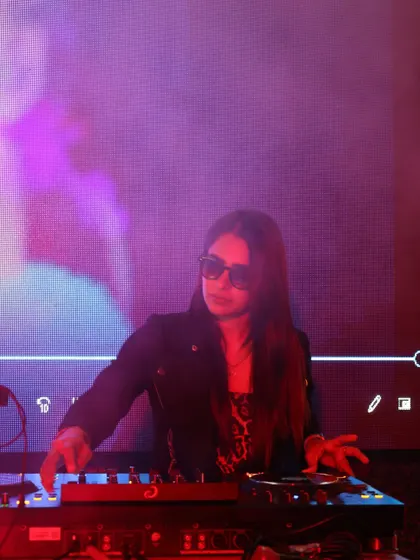 Mixing under moody purple lighting, fully in the zone. This photo captures the intense concentration that goes into crafting a seamless DJ set.