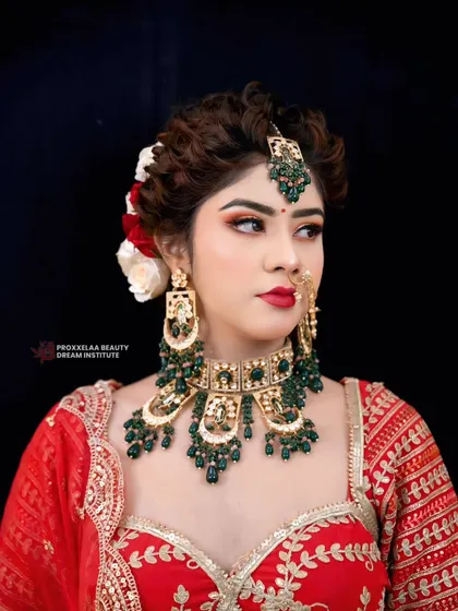 A powerful bridal portrait. The combination of a bold red lip, sharp contour, and emerald green jewelry creates a look of undeniable confidence.