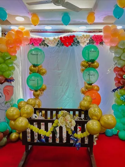 Another angle of the jungle themed naming ceremony, showing the colorful balloon arch and the placement of the animal cutouts around the central cradle.