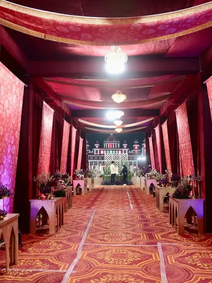 The entrance walkway was designed to feel like a royal passage. Lined with rich red drapes, patterned carpets, and elegant console tables with floral arrangements, it set a grand tone for the wedding.