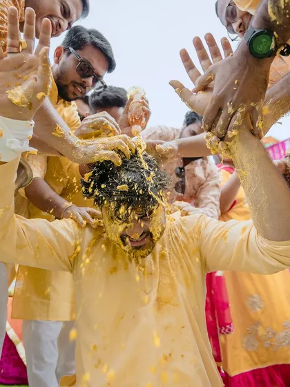 A dynamic shot from above as the groom gets a head full of haldi. This photo captures the messy, joyful reality of the celebration.