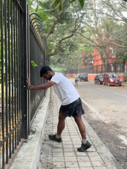 Performing a calf stretch against a fence. Static stretching is important during the cool-down phase to improve flexibility.