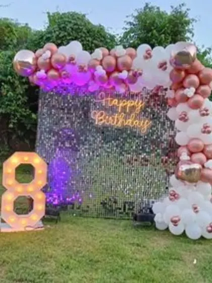 An outdoor 18th birthday party with a silver sequin wall. The rose gold and white balloon arch and large marquee numbers create a stunning evening look.