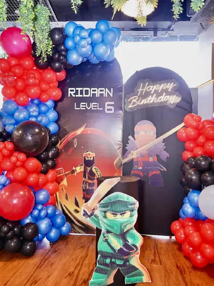 Level up your party with a Roblox or Ninjago theme. This setup features dynamic character backdrops and a bold color scheme of red, blue, and black balloons for an action-packed celebration.