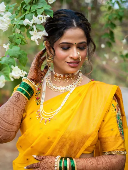 A vision of tradition and grace in a radiant yellow saree. The makeup is soft and glowing, with a focus on her eyes and the beautiful pearl-and-gold jewellery.