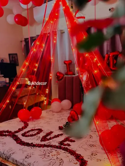 A close-up view from the foot of the bed, showing the "LOVE" petal arrangement under the glowing canopy. We focus on small details like the single rose to make the moment perfect.