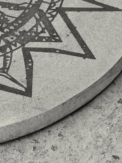A detail of the edge of the concrete art table, showing the smooth, hand-finished curve of the tabletop.