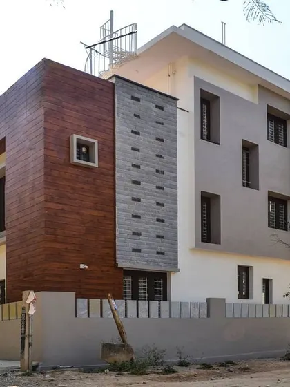 The finished exterior of a residence in Haralur, where wood-look cladding provides a warm contrast to the white and grey structure. This project shows the successful translation of a contemporary 3D design into a built reality.