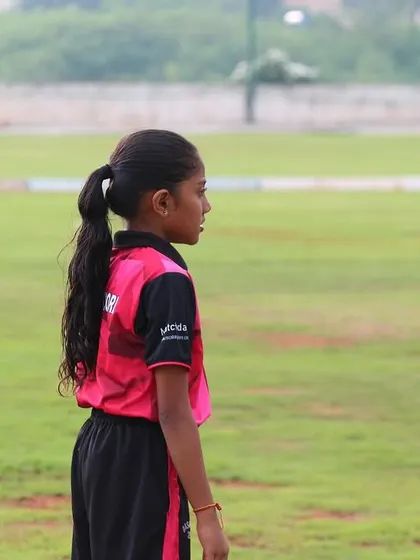 A young fielder maintains her focus on the game, ready to react to any opportunity.