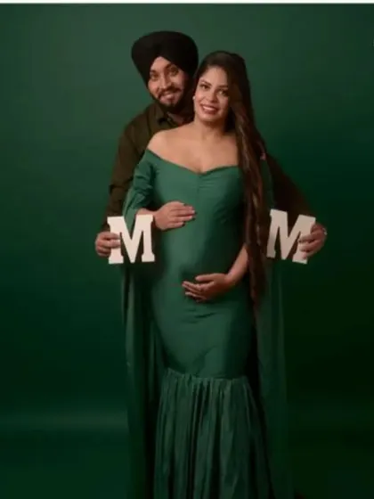 A couple's portrait featuring the bottle green mermaid gown. The "MOM" letters add a sweet, personal touch to this classic studio maternity photo.