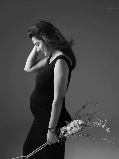 A candid smile and a simple prop. Holding flowers adds a touch of softness to this beautiful black and white side-profile portrait.