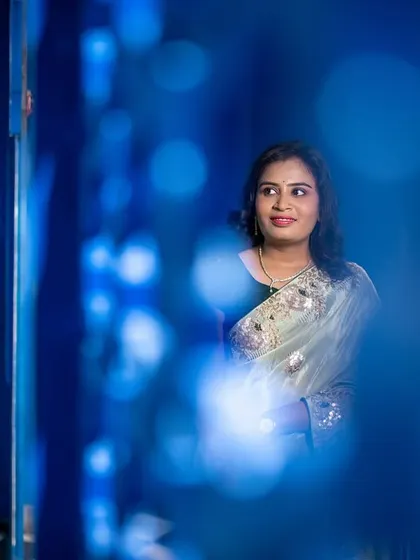 An artistic shot using a foreground blur to create a sense of looking in on a private moment. The blue background adds a pop of color and style.