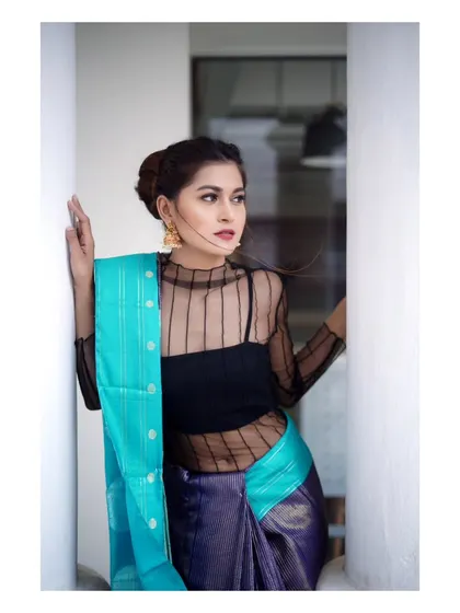 A modern interpretation of saree fashion. The sheer top paired with a traditional Kanchipuram saree creates a contemporary and stylish look, captured with soft, natural light.