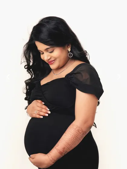 A simple, beautiful portrait against a clean white background. Her gentle smile and the henna on her arm add a lovely personal touch.
