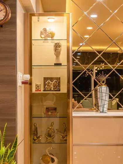 This Mumbai home is the definition of modern luxury, featuring a stunning display cabinet with gold trim and a beveled mirror wall in the dining area.