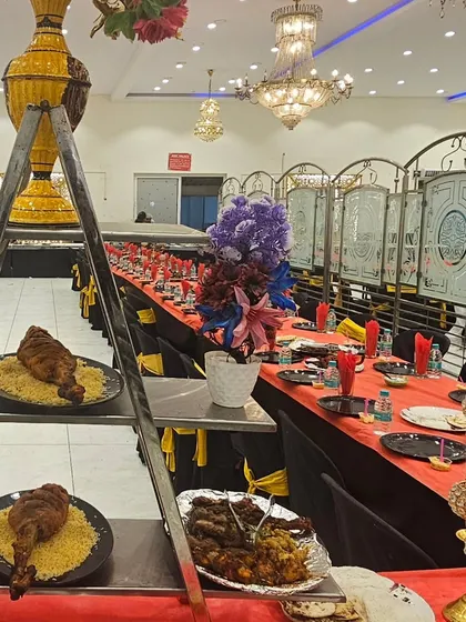 A unique presentation for a groom's table, featuring a tiered ladder stand. This setup showcases our whole roasted chicken on a bed of rice, alongside platters of our signature charcoal-grilled kebabs.