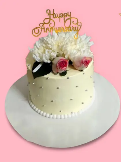 A chic and simple anniversary cake topped with a "Happy Anniversary" pick and fresh white chrysanthemums. This minimalist design is perfect for a modern and stylish celebration in Delhi.