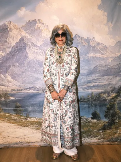 A full-length portrait of Zeenat Aman against the scenic backdrop, showcasing the entire elegant ensemble.
