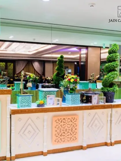 A vibrant and colourful buffet setup for a festive occasion. The pastel-coloured counters with intricate latticework and topiary decor create a cheerful and welcoming food station.