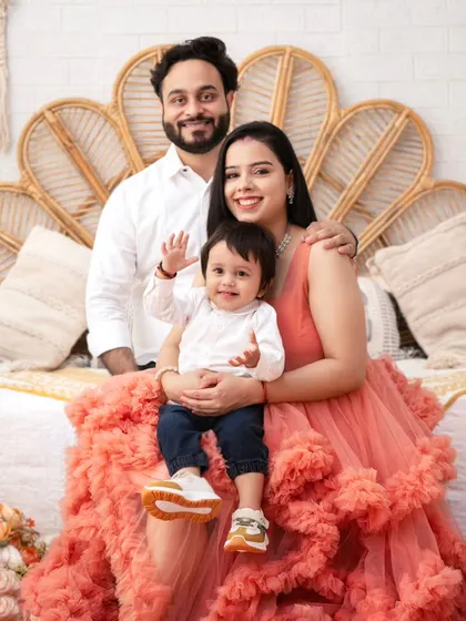 A perfect family portrait, full of smiles and warmth. The ruffled dress on the mother adds a touch of high-fashion elegance to the scene.