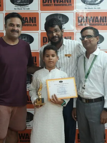 A student stands with his father and teachers, a complete support system celebrating his win.