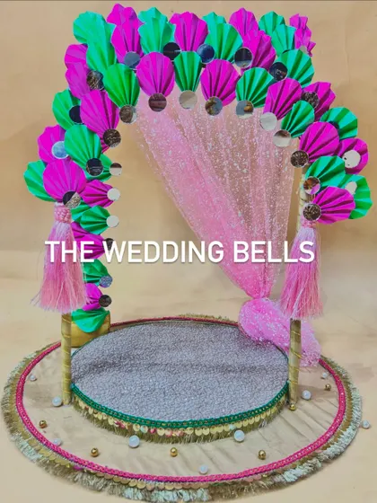 This Ganesha mandap design features a shimmering pink sequin backdrop, perfectly complementing the vibrant paper fan arch. It's a festive and glamorous choice for your Ganesh Chaturthi celebrations.