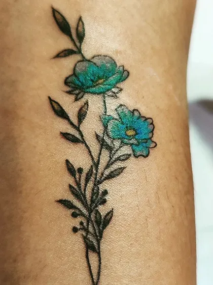 A close-up of a delicate floral tattoo. I used a mix of fine black lines for the stem and leaves, with a pop of turquoise blue for the flowers to create a beautiful contrast.