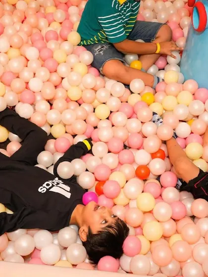 A boy lies back and relaxes in the ball pit, completely immersed in fun.