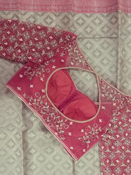 This pink blouse features two different embroidery styles. The sleeves have a geometric pattern while the body has a delicate floral vine design.