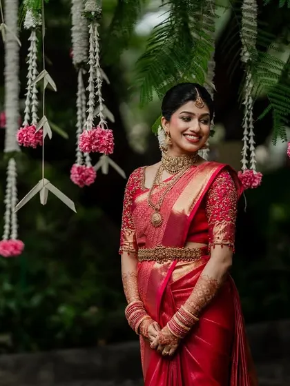 A beautiful South Indian bride ready for her big day. The intricate details of her red saree and the delicate floral decor create a picture of timeless elegance.