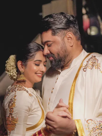 A close-up of the coordinated Diwali look. You can see the matching embroidery on her blouse sleeve and his kurta shoulder, tying the two outfits together beautifully.