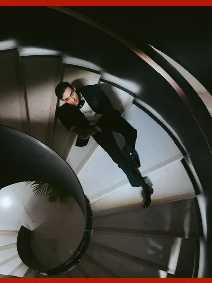 A creative perspective for a groom's portrait. This top-down shot on the spiral staircase creates a dynamic and artistic composition, showcasing his dapper tuxedo.