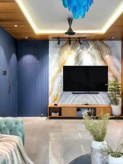 This living room features a striking blue accent wall with fluted paneling, paired with a marble-patterned TV backdrop. The design is bold and contemporary, with a wood ceiling detail that adds warmth.