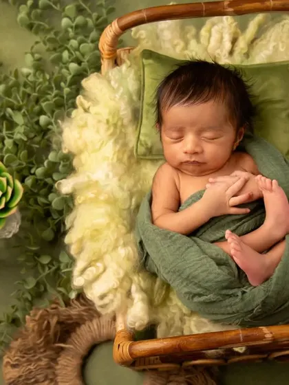 A slightly different angle of the green botanical theme, showcasing the baby's peaceful pose and the rich textures of the wraps and surrounding props.