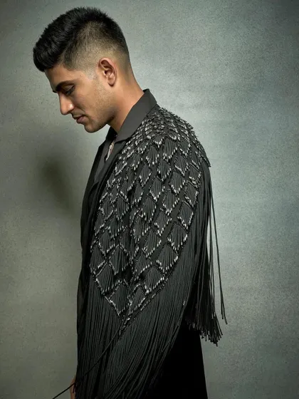 A profile shot of Shubman Gill, where the focus is on the unique, textured shoulder panel of his fringed jacket. It’s a perfect example of how I use unconventional details to make a look memorable.
