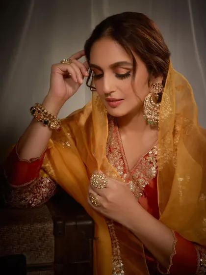 A close-up portrait highlighting the intricate gold embroidery and the stunning statement jewelry. The soft organza dupatta adds a layer of delicacy to this royal look.