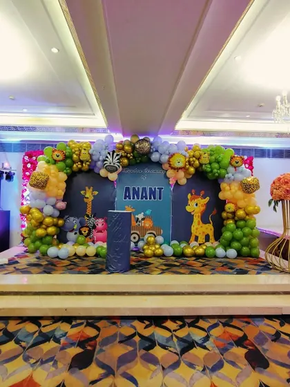 The complete stage view for the jungle-themed Mundan party. The setup includes the main backdrop, stage flooring, and large floral vases on the sides.