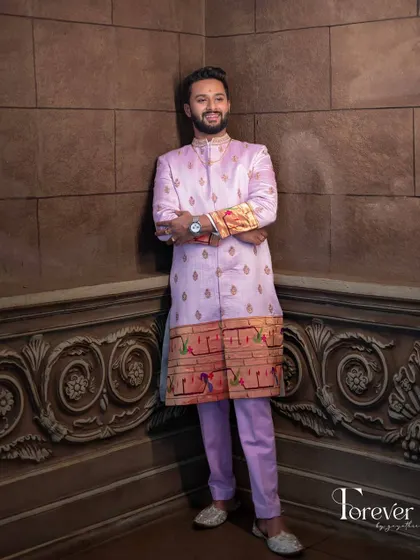 This is a full view of the Paitani silk sherwani in a unique lavender shade. The fit is tailored to be sharp and flattering, while the traditional border adds a touch of heritage and color.