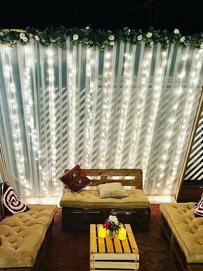 A cozy and rustic lounge area we created for guests to relax. The seating is made from wooden pallets with comfortable cushions, set within a teepee-style frame decorated with fairy lights.