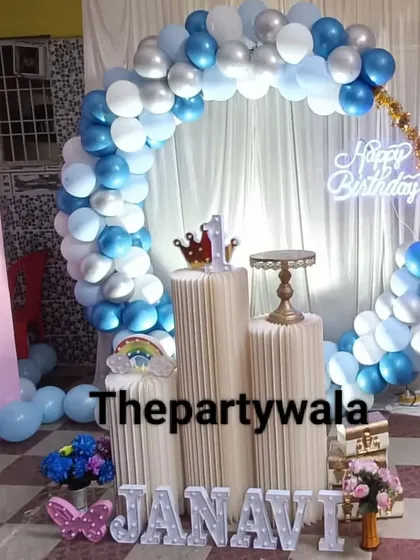 A blue and white balloon ring with a 'Happy Birthday' neon sign, ideal for a first birthday party.