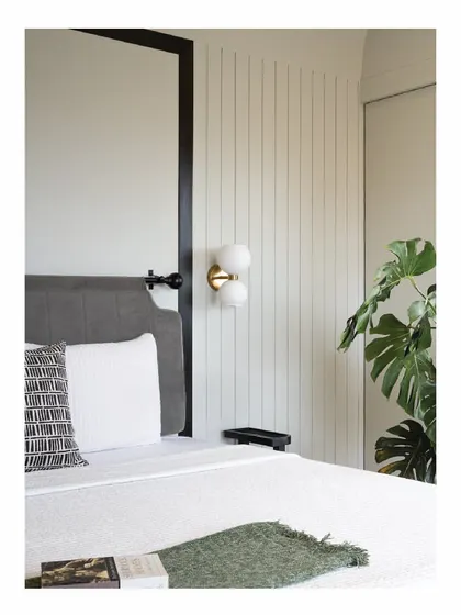 A bedside corner in the 'Powai House'. We designed the headboard and selected this modern wall lamp to create a calm, functional space. The vertical paneling behind the bed adds texture and visual height to the room.