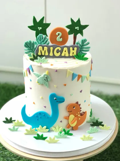 A "rawr-some" dinosaur cake for a second birthday, featuring cute, friendly dinosaurs in a prehistoric setting.