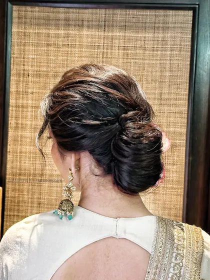 A textured messy bun with loose tendrils, perfect for a more relaxed and romantic vibe. This style is great for a garden wedding or an outdoor event.