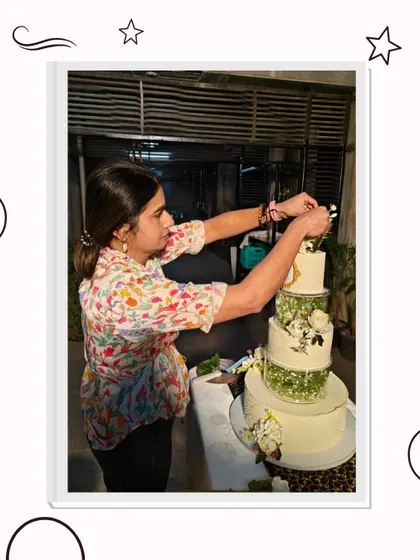 The final touches are always the most important. Here, I am carefully placing the last few sugar flowers on a large wedding cake, ensuring every detail is perfect before it goes to the client.