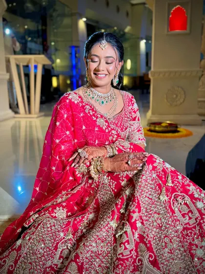 A joyful bride with her hair styled in a floral bun. This timeless updo is a popular choice for its elegance and ability to hold heavy dupattas and jewellery in place.