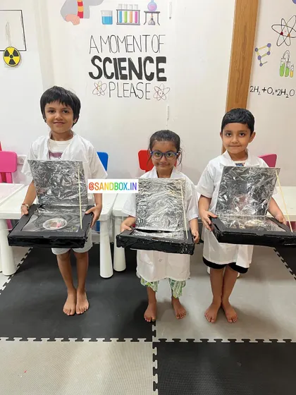 Our young scientists proudly present the solar cookers they built. This project teaches them about renewable energy and the power of the sun in a practical way.