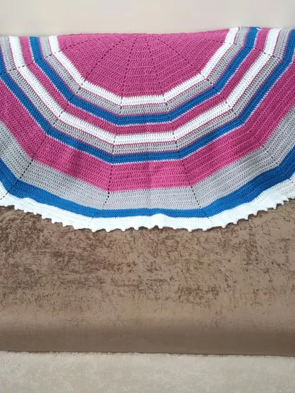 My fuschia and grey semi-circle shawl resting on a couch. This view shows the classic shape that drapes beautifully over the shoulders.